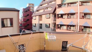Une terrasse sur le toit équipée d’un lave-linge, de supports à linge et offrant une vue sur les bâtiments environnants.