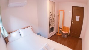 Une chambre d’hôtel avec un grand lit, un miroir, un petit tabouret et un plateau contenant des serviettes et des articles de toilette.