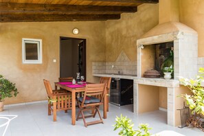 A dining area with a table and chairs, a built-in oven, and a potted plant. - 9 km from the sea, free Wi-Fi, barbecue, dishwasher, washing machine (Grandići)