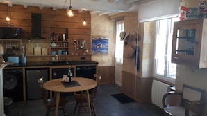 Una cocina con armarios de madera, una mesa de comedor con sillas y una ventana con vista al mar.