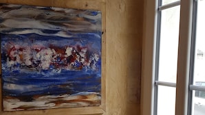 Una habitación con pared de paneles de madera, una ventana y un cuadro.