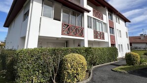 A two-story building with a white facade, brown roof, and a balcony with a lattice design. - Cozy Ground Floor Studio, Terrace, Parking, Pet-Friendly - Cambo-les-Bains (Cambo-les-Bains)