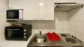 A compact kitchen with white cabinets, a microwave, a toaster, a sink, and a stove. - Cozy Ground Floor Studio, Terrace, Parking, Pet-Friendly - Cambo-les-Bains (Cambo-les-Bains)