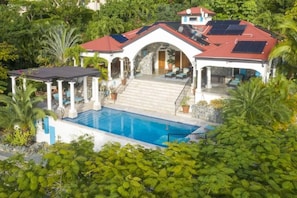 A house with a swimming pool, covered patio, and solar panels.