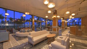 A spacious lobby with a large seating area, a reception desk, and large windows offering a view of palm trees and the ocean. - Cocoland River & Beach Resort (Tu Nghia)