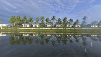 A waterfront property with multiple houses, palm trees, and a calm reflective water surface.