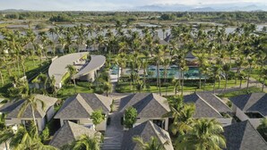 A resort with modern architecture, a swimming pool, and lush palm trees. - Cocoland River & Beach Resort (Tu Nghia)