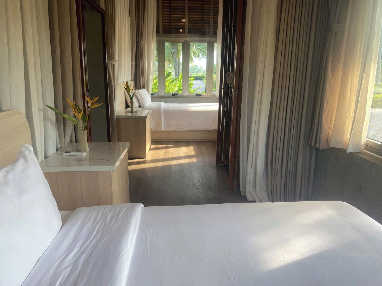 Une chambre d’hôtel avec un lit, une table de chevet, une lampe et une vue sur la verdure.