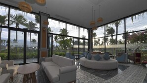 A spacious lounge area with large windows, a round seating area, and a patterned rug. - Cocoland River & Beach Resort (Tu Nghia)