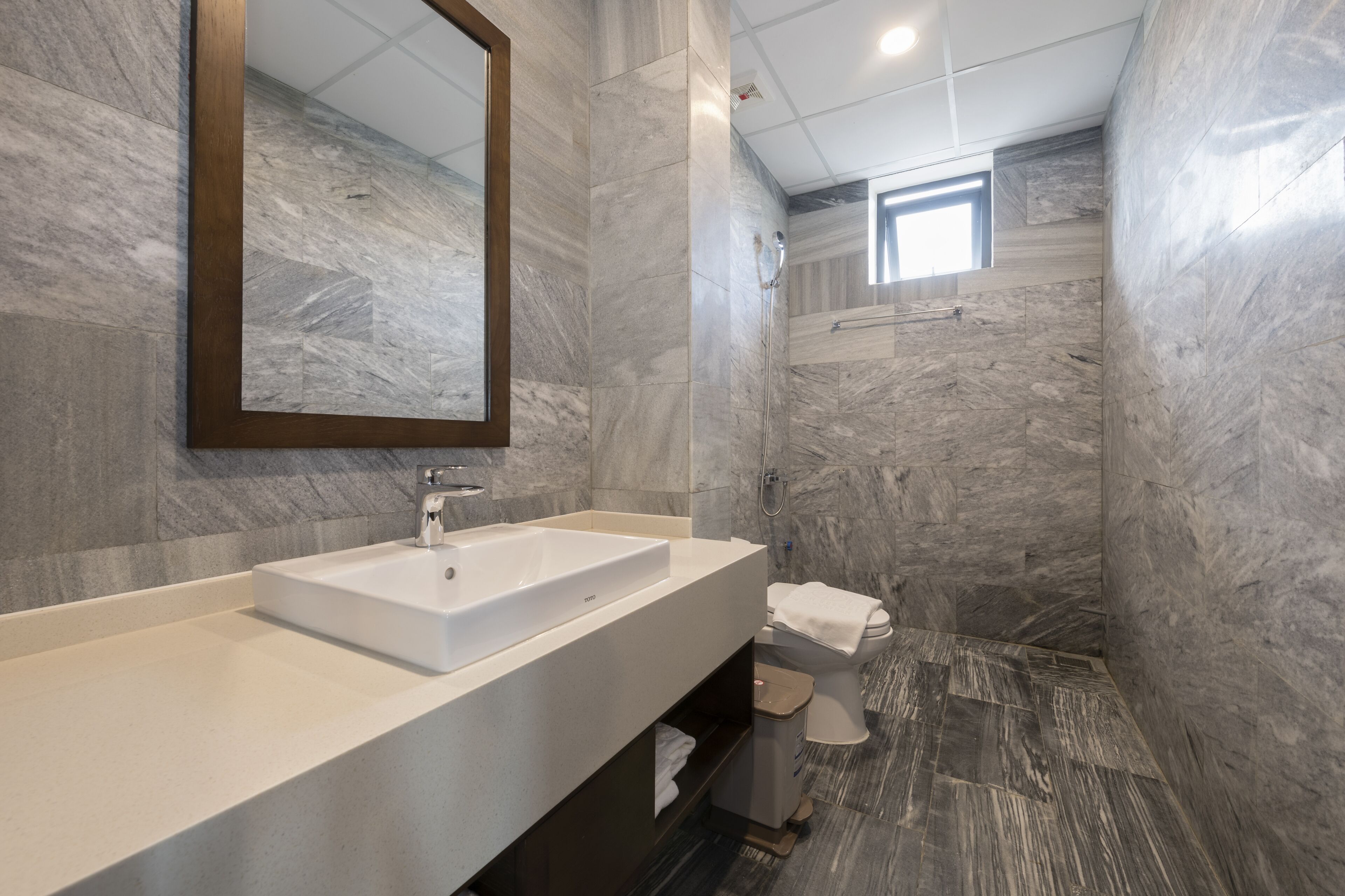 A modern bathroom with a large sink, mirror, and shower area.