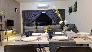 Un espace de salle à manger moderne avec une table dressée pour quatre personnes, un ventilateur de plafond et un climatiseur fixé au mur.
