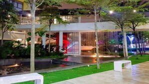 Un bâtiment moderne doté d’une façade en verre, d’une terrasse et d’un élément décoratif aquatique.