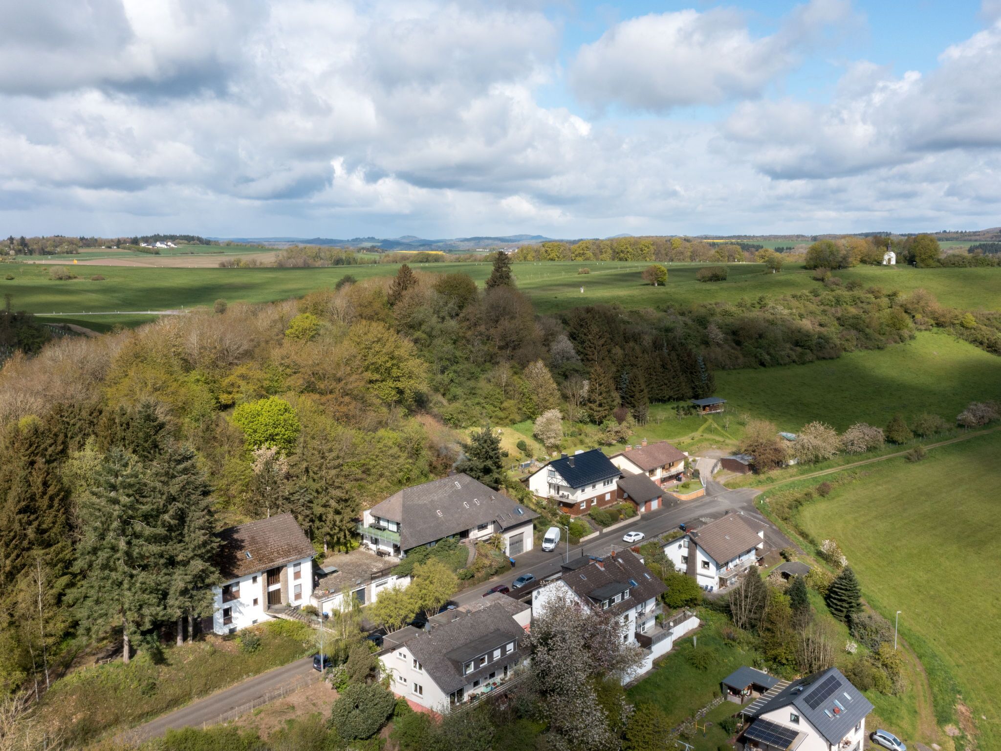 An aerial view of a residential area with houses, roads, and green fields.