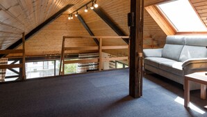 An attic room with a sloped ceiling, a grey sofa, a wooden ladder, and a skylight. - Eifelnatur (Haus 2) by Interhome (Immerath)