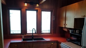 Een compacte keuken met houten kastjes, een ingebouwde vaatwasser en een raam met uitzicht.