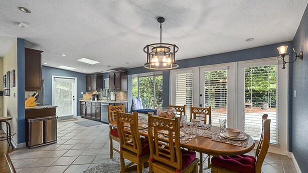 A spacious kitchen with a dining area, featuring a large island, wooden chairs, and a chandelier. -  Family & Pet Friendly (*additional pet fee will apply), Charming Orlando Home! (Orlando)