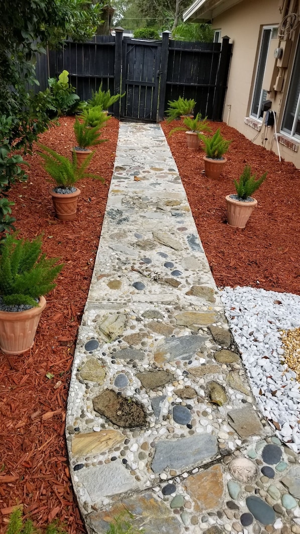 A stone pathway leading to a house with a black fence and potted plants on either side. -  Family & Pet Friendly (*additional pet fee will apply), Charming Orlando Home! (Orlando)