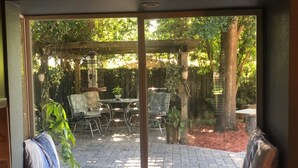 A patio with a table and chairs, surrounded by plants and a wooden pergola. -  Family & Pet Friendly (*additional pet fee will apply), Charming Orlando Home! (Orlando)