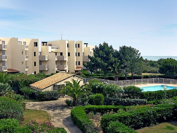 A residential building with multiple balconies, a swimming pool, and well-maintained gardens.