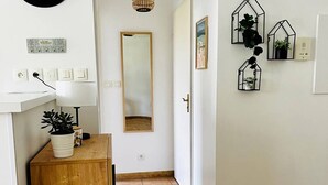 Ein Flur mit einem Holzschrank, einem Spiegel, einer Topfpflanze und Wandleuchten.