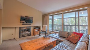 A living room with a fireplace, a sofa, a coffee table, and a television mounted on the wall. - Last Minute Holiday Rates! Panoramic views from Balcony (Keystone)