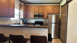 Cucina con mobili in legno, elettrodomestici in acciaio inossidabile e una porta scorrevole.