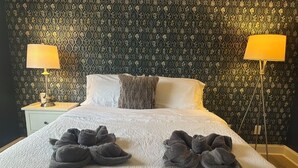 Un letto rifatto con un copriletto bianco e due asciugamani grigi piegati sopra.