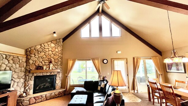 Una sala de estar acogedora con chimenea de piedra, televisor y comedor con mobiliario de madera.