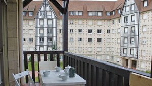En balkon med et bord og stole, med udsigt over en række traditionelle bindingsværkshuse.