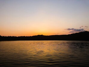A calm lake at sunset with a silhouette of a forested hill in the background. - Perfect Lake Hartwell Getaway - Gorgeous Lake Views! (Seneca)