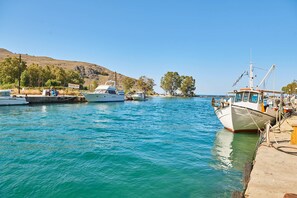 A marina with several boats docked, a clear sky, and a hilly landscape in the background.