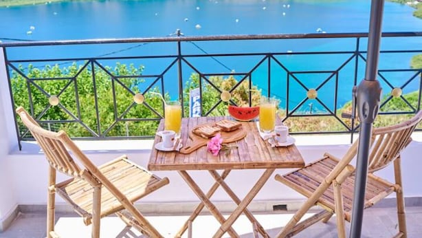 Una mesa de madera con alimentos para el desayuno y vistas a un lago.