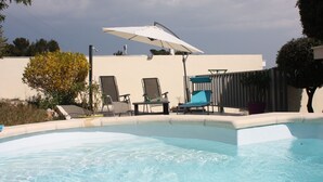 Una piscina con lettini e un ombrellone.