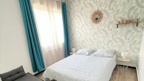 Una camera da letto con un letto, una panca, un comodino, una mensola a muro e carta da parati fantasia.