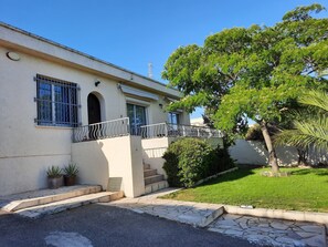 A two-story building with a balcony, potted plants, and a well-maintained lawn.