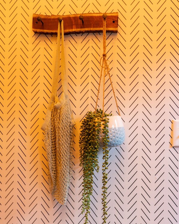 A wall-mounted wooden rack with a hanging net and a potted plant.