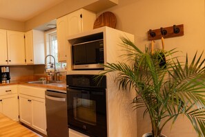 A kitchen with white cabinets, a microwave, an oven, and a sink.