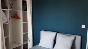 A bedroom with a bed, a wardrobe, and a blue wall.