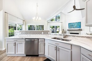 A spacious kitchen with white cabinetry, a large island, and a ceiling fan. - 21 Shell Ring:  BESTNEST by Beverly Serral Vacation Rentals (Hilton Head Island)