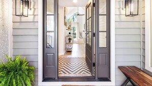 A house entrance with a checkered floor mat, a bench, and two wall-mounted lanterns. - 21 Shell Ring:  BESTNEST by Beverly Serral Vacation Rentals (Hilton Head Island)