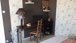 Makuuhuone, jossa on sänky, työpöytä tuolilla, lamppu, kirjahylly ja taulu seinällä.
