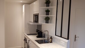 A modern kitchen with white cabinetry, a stainless steel sink, and a built-in oven.