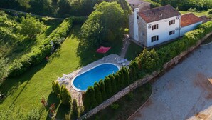 An aerial view of a property with a swimming pool, stone house, and lush greenery. - Walnut House with a pool (Nedešćina)
