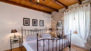 A bedroom with a metal bed frame, a stone wall, and a wooden ceiling. - Walnut House with a pool (Nedešćina)