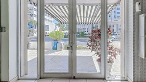 L’entrée d’un hôtel avec une porte en verre, un espace extérieur abrité et un pot de fleurs.