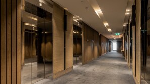 Un pasillo con paneles de madera, puertas espejadas y suelo alfombrado.