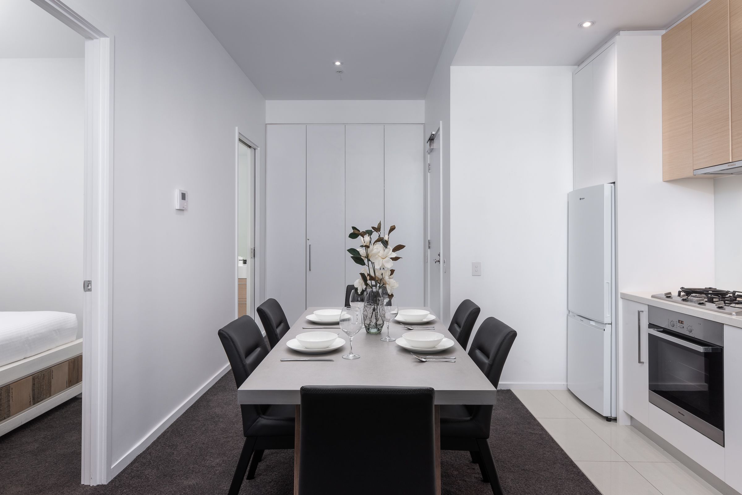 A modern kitchen with white cabinets, a built-in oven, and a gas stove.