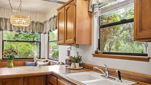 Una cucina con pensili in legno, un lavello doppio e una finestra vista verde.