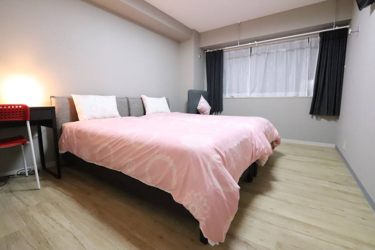 A bedroom with a bed, a desk, and a chair.
