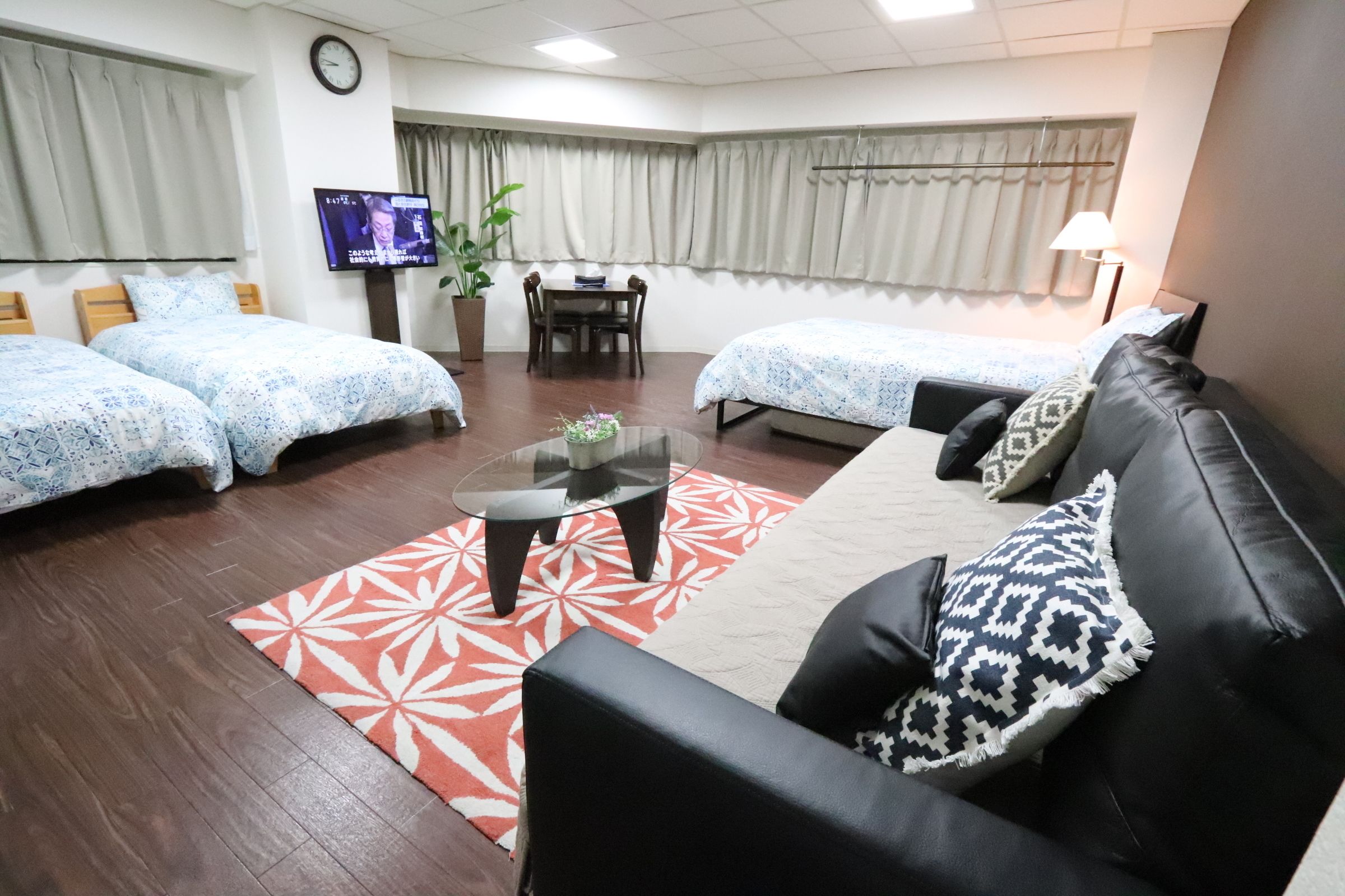 A hotel room with two beds, a sofa, a small table, and a TV.